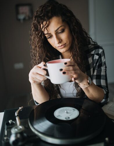 Una mujer escucha un disco de vinilo mientras toma un café